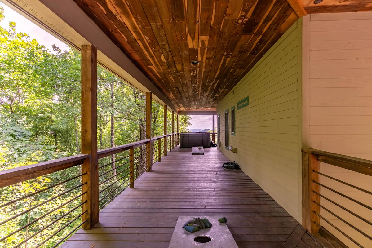 This image captures an inviting wooden deck featuring a hot tub and wooden railing, surrounded by lush greenery. The scene exudes tranquility and showcases a comfortable outdoor space for relaxation after a day of adventure.